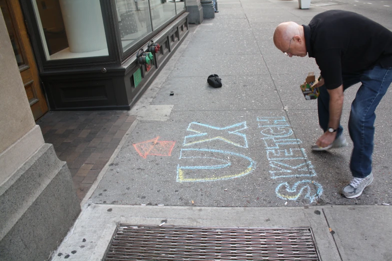 a man writing a message on the pavement with graffiti