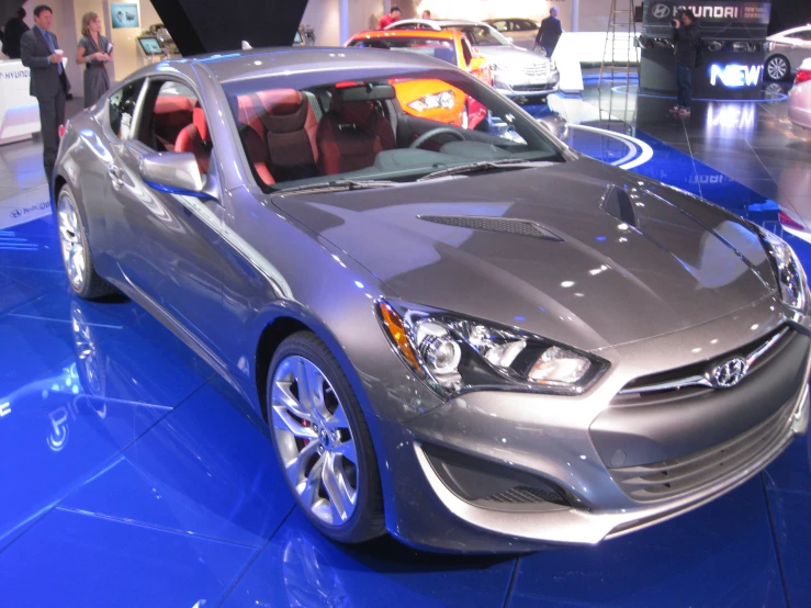 a silver sports car is displayed on the blue carpet