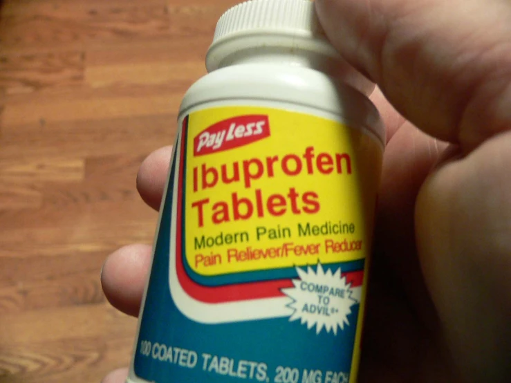 a person holding up a bottle of liguloen tablets