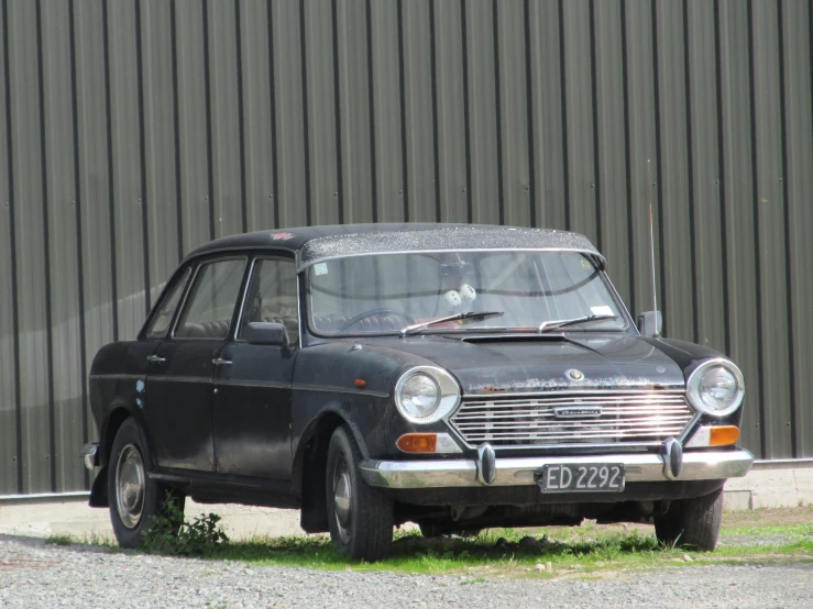 an old grey car with no wheels parked on the side of the road