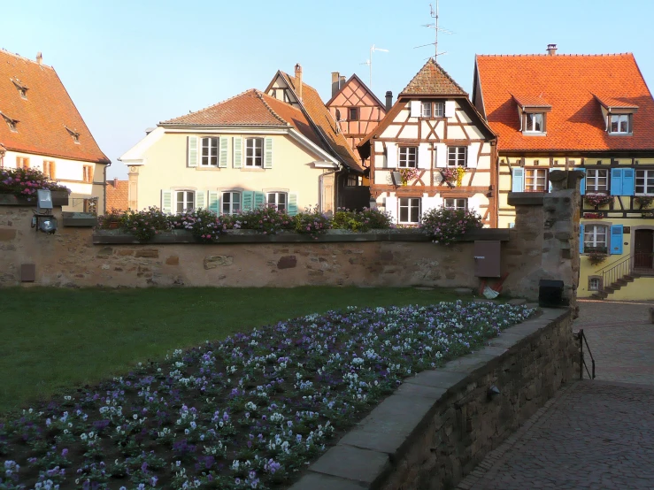 a city with flowered beds in front of a very tall brick wall