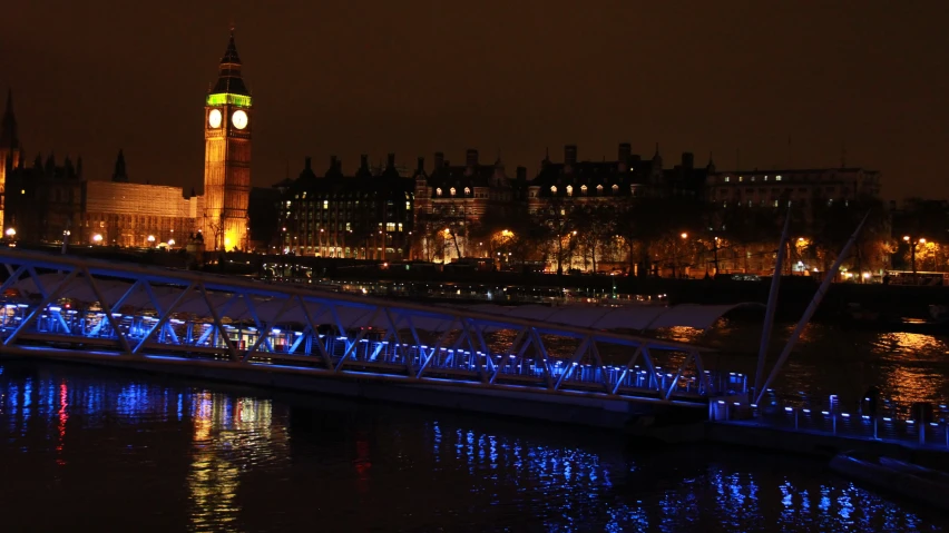 a bridge going across a river with a clock tower in the distance