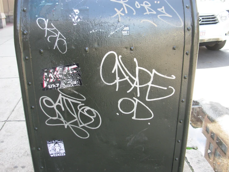 a metal box on the sidewalk that has graffiti all over it