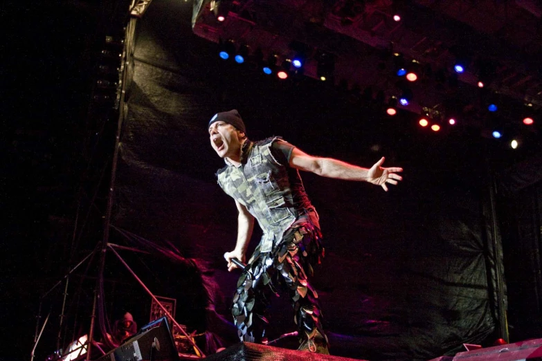 a person on stage with his arms out and one hand up