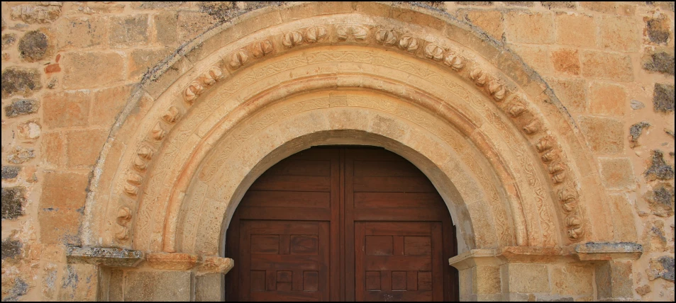 a tall wooden door next to a stone wall