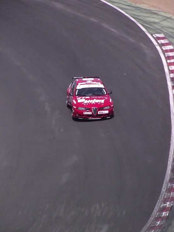 a red car driving around a track in a race
