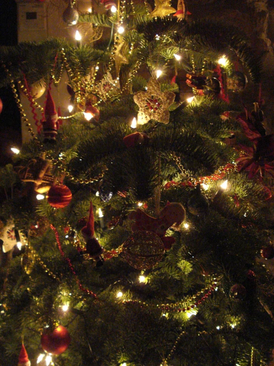 lit christmas tree with lots of baubies in the dark