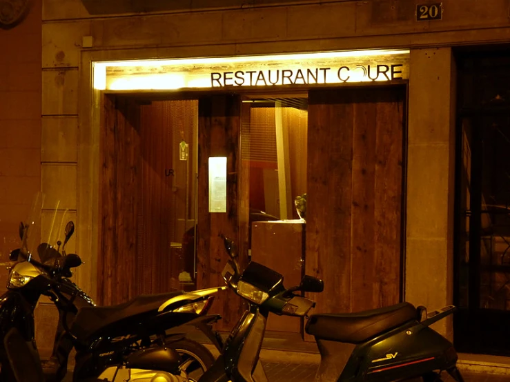 motorcycle parked in front of a restaurant lit up at night