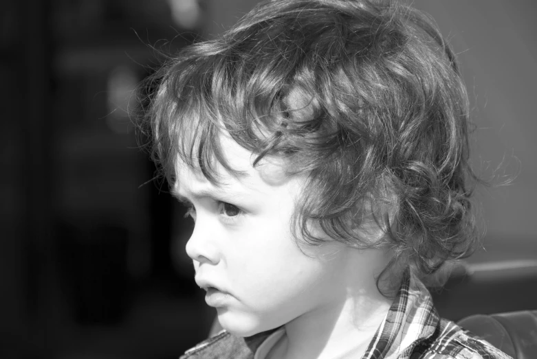 a small child with curly hair looks over his shoulder