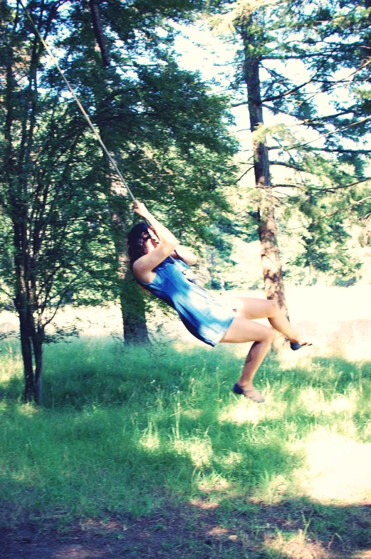 young women hanging on a rope in the woods