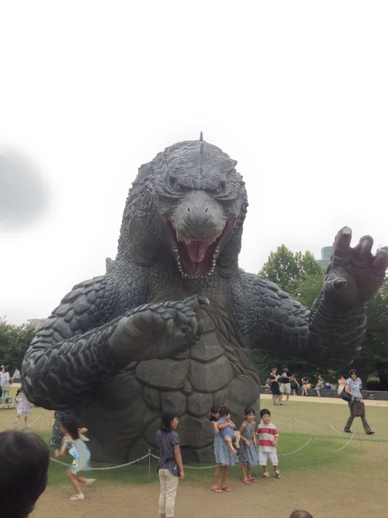 people are gathered around a large inflated godzilla