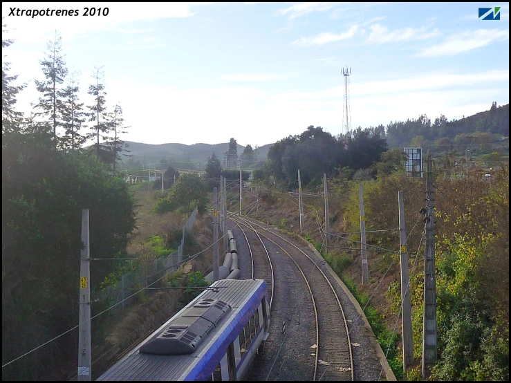 a train is seen going down the tracks near trees and hills