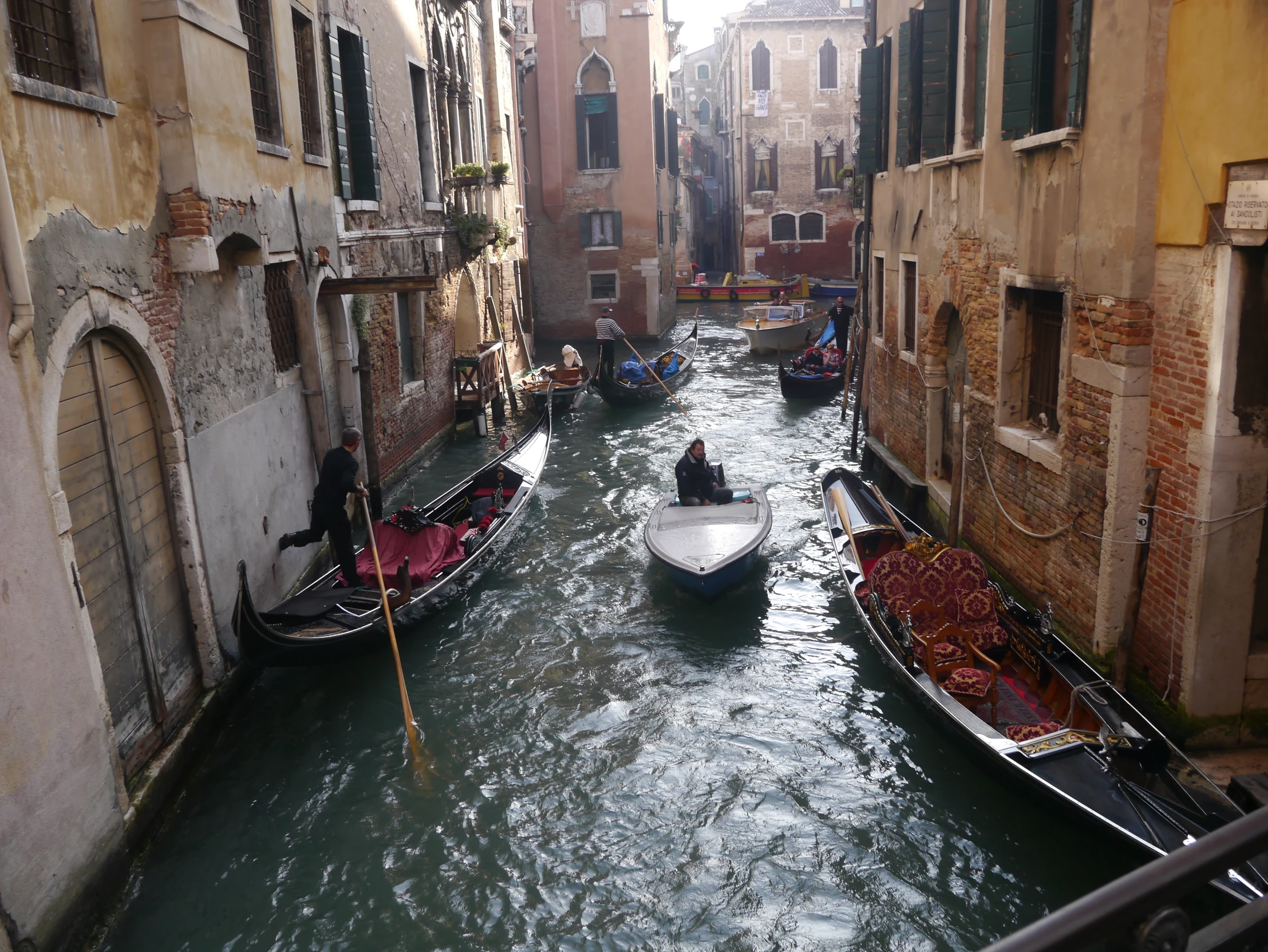 a narrow waterway with gondolas and people in a boat