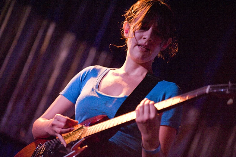 the woman is playing an electric guitar on stage