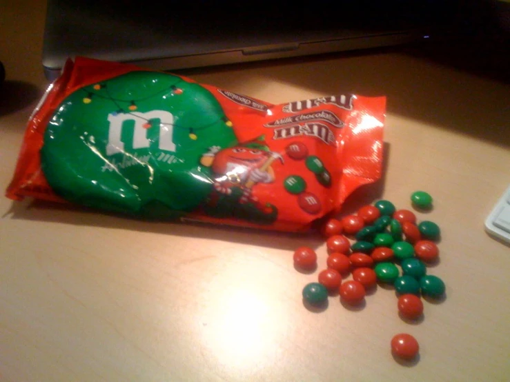 a bag of m & ms chocolate candy with a couple mints next to it