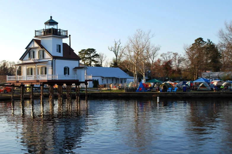 a lighthouse sits on a dock next to houses