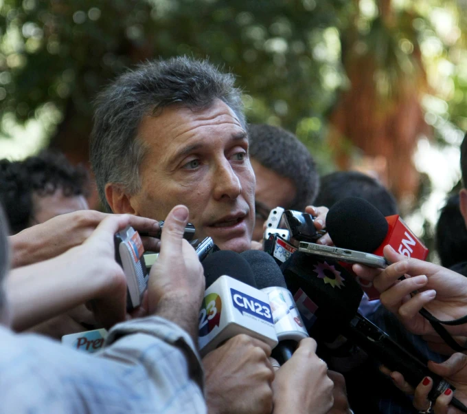 a man is surrounded by reporters and holding microphones