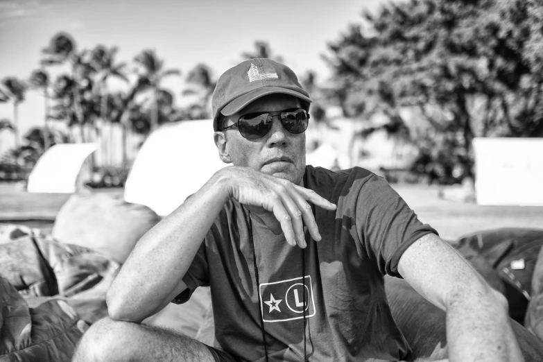 man in shades sits on a couch with palm trees behind him