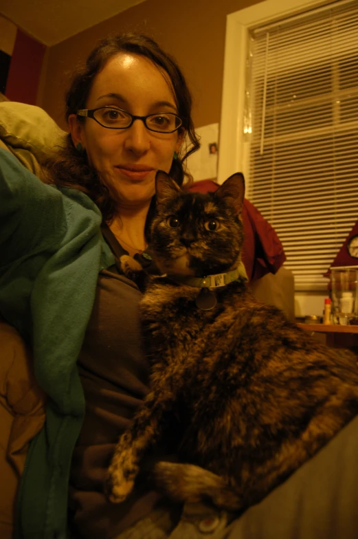 a woman wearing glasses holding her cat