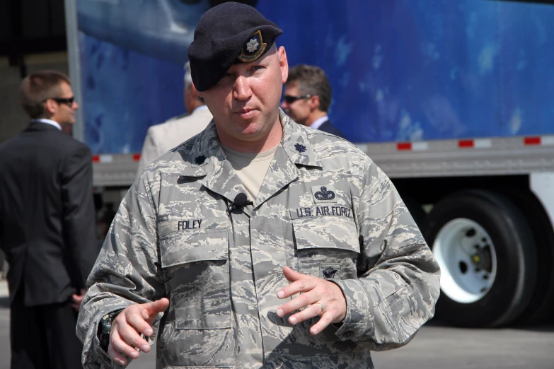 a soldier is talking in front of a truck