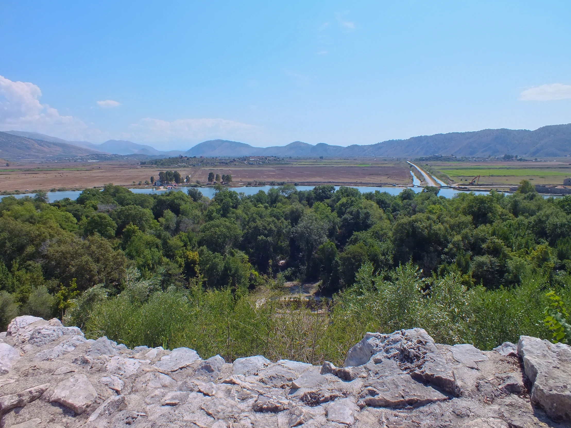 a lush green hillside with a blue body of water