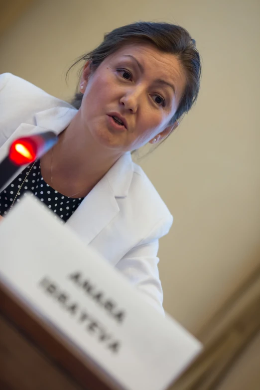 a woman stands in front of the microphone with a red light on her face