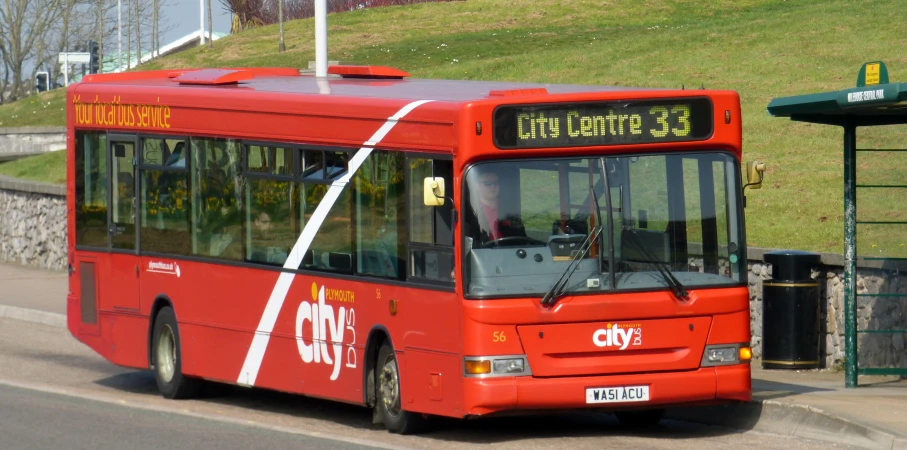 an orange and red bus driving down the street