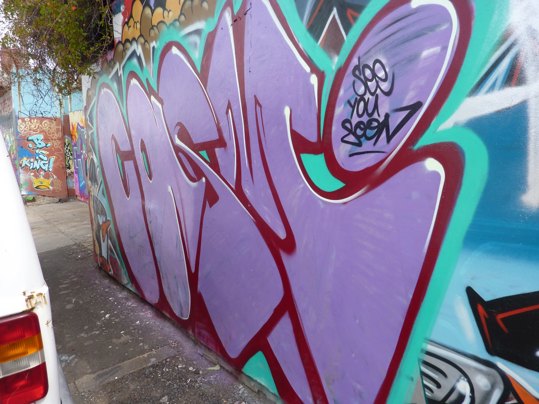 a white car parked by some graffiti on a wall