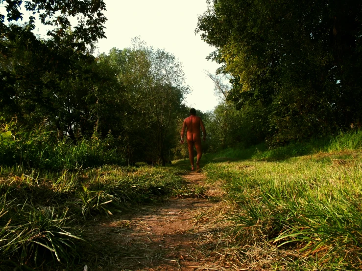 a woman walking down a dirt road with some trees