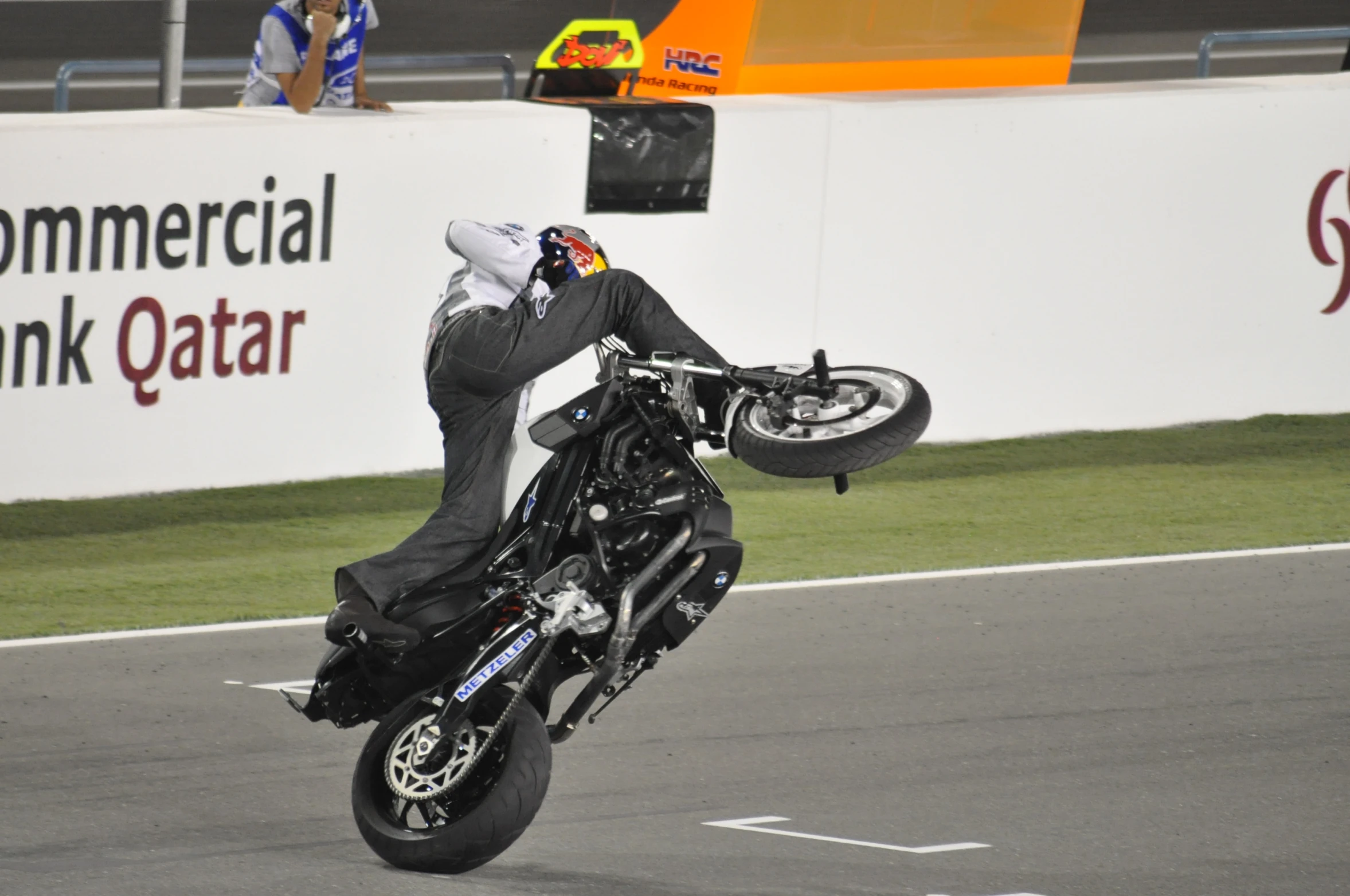 a man riding a motorcycle holding onto his helmet