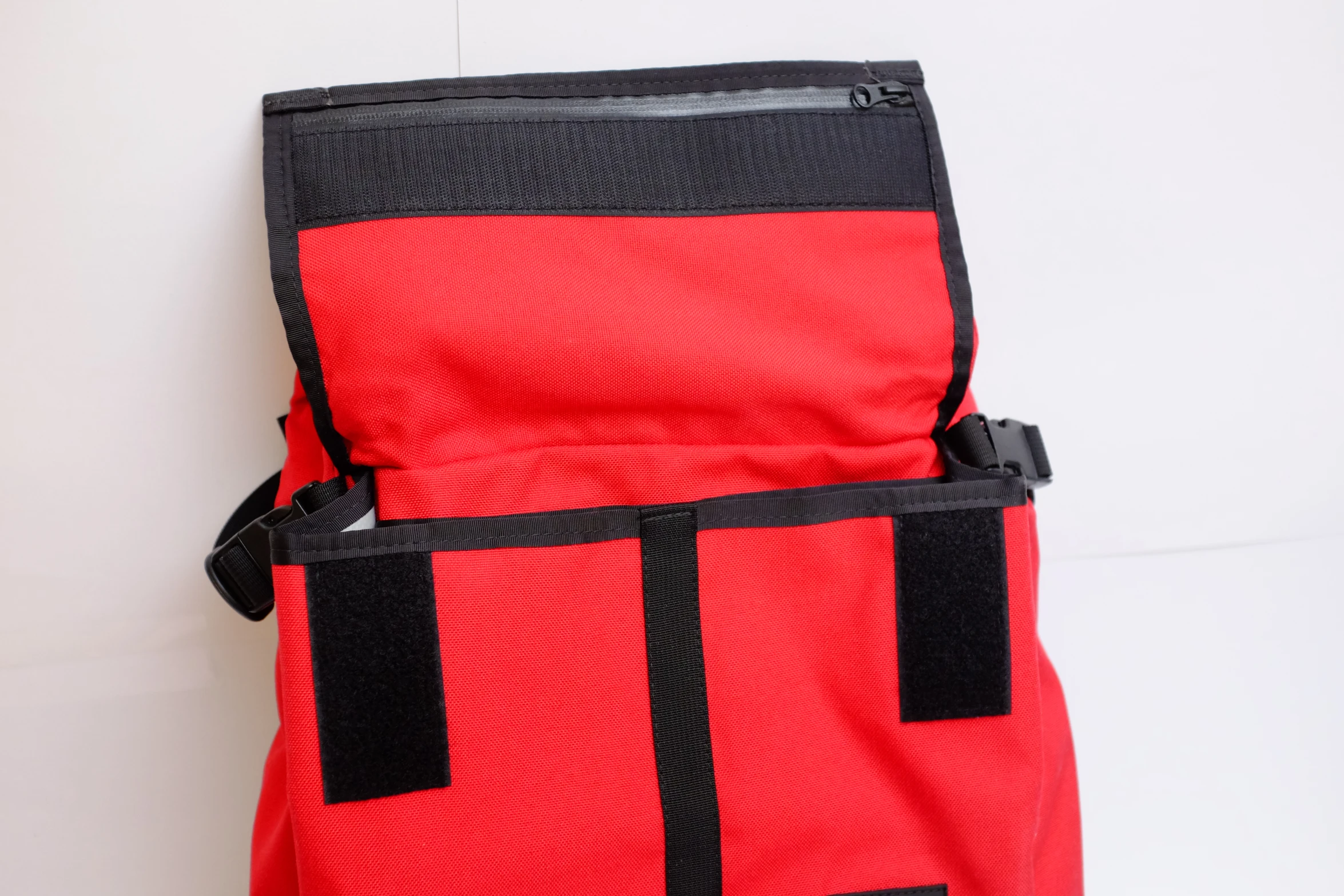 a red backpack with black handles and some straps