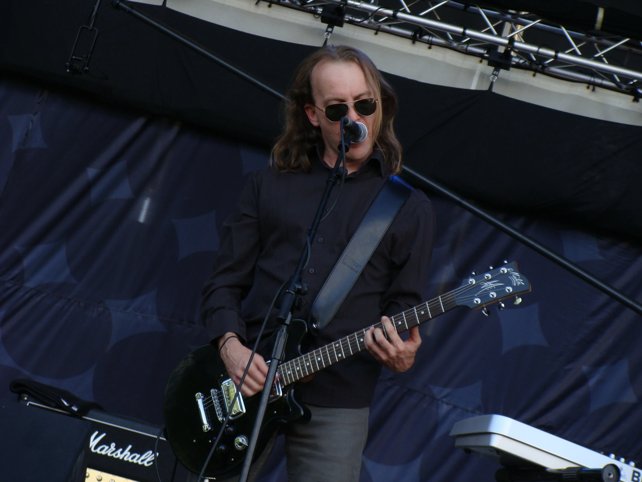 man singing and playing guitar on stage with microphone