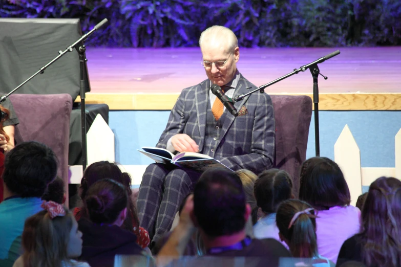 an old man sitting in a chair reading a book