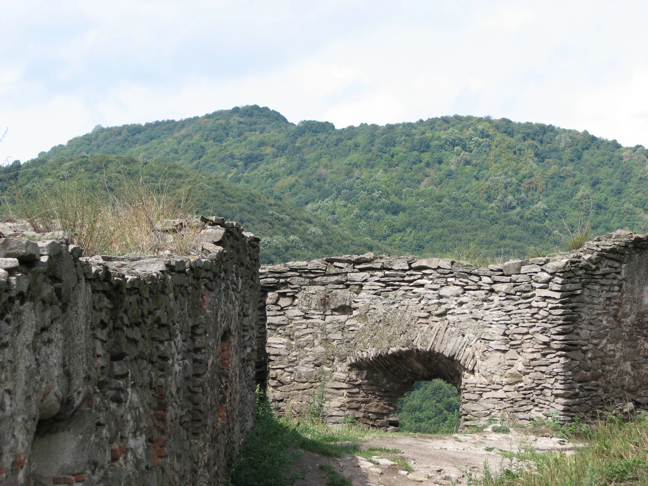 a small, stone archway to a building near mountains