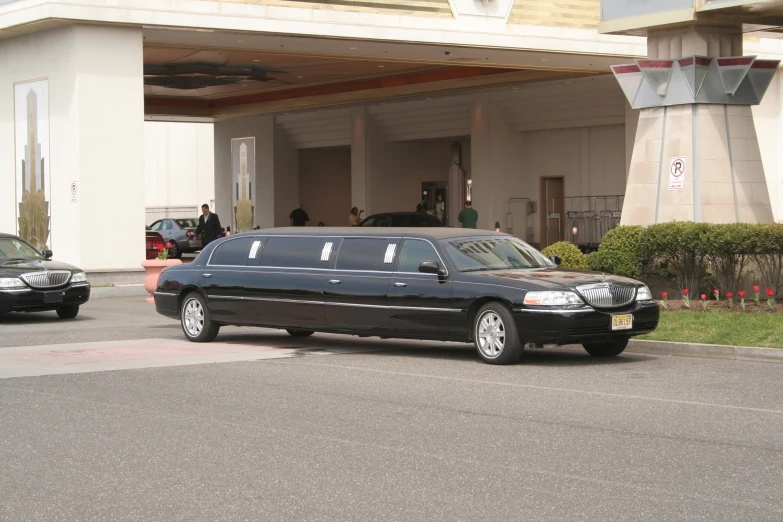 the limo is parked at the curb in front of the large building