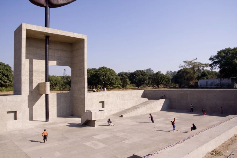 a concrete clock tower with people sitting around