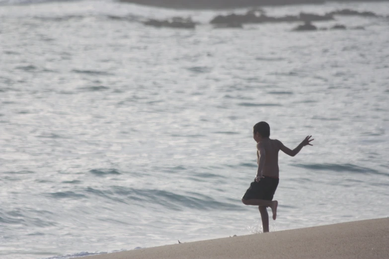 a boy is playing on the beach by the water