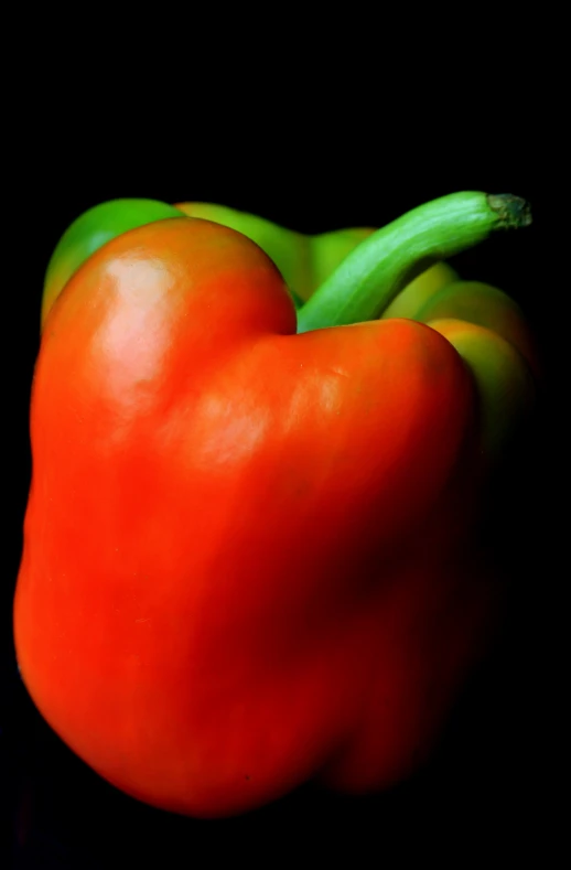 a large red pepper on top of a green pepper