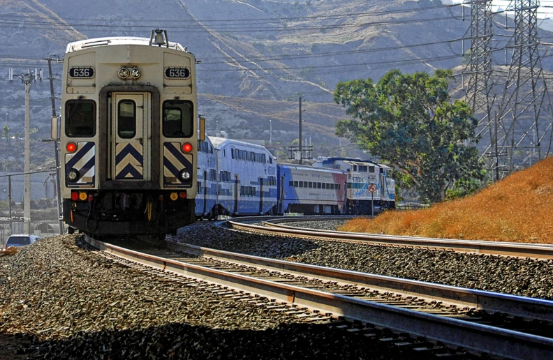 a train is coming down the tracks with hills in the background