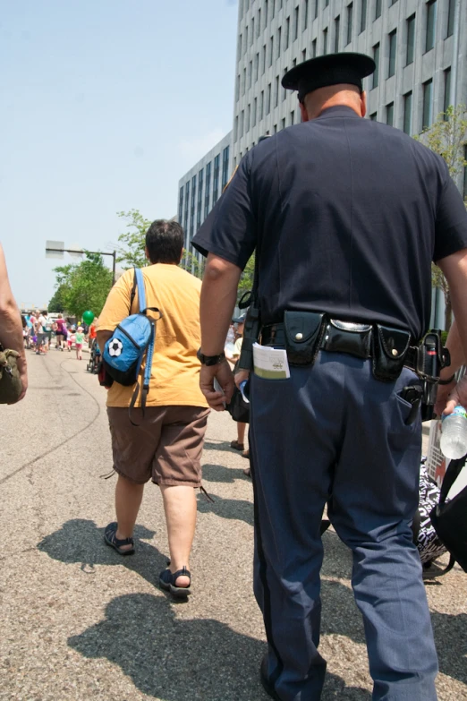 a police officer walking down the street while holding on to a back pack