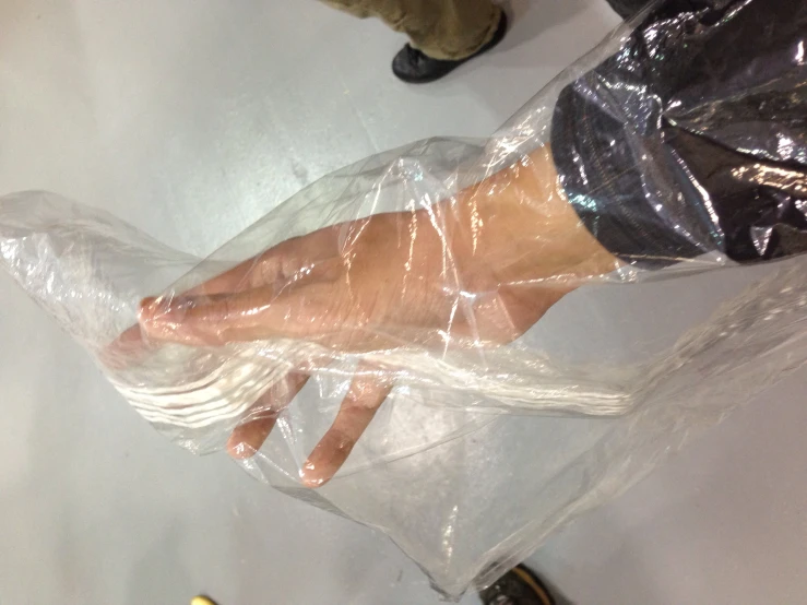 a person's hand wrapped in plastic over their left leg