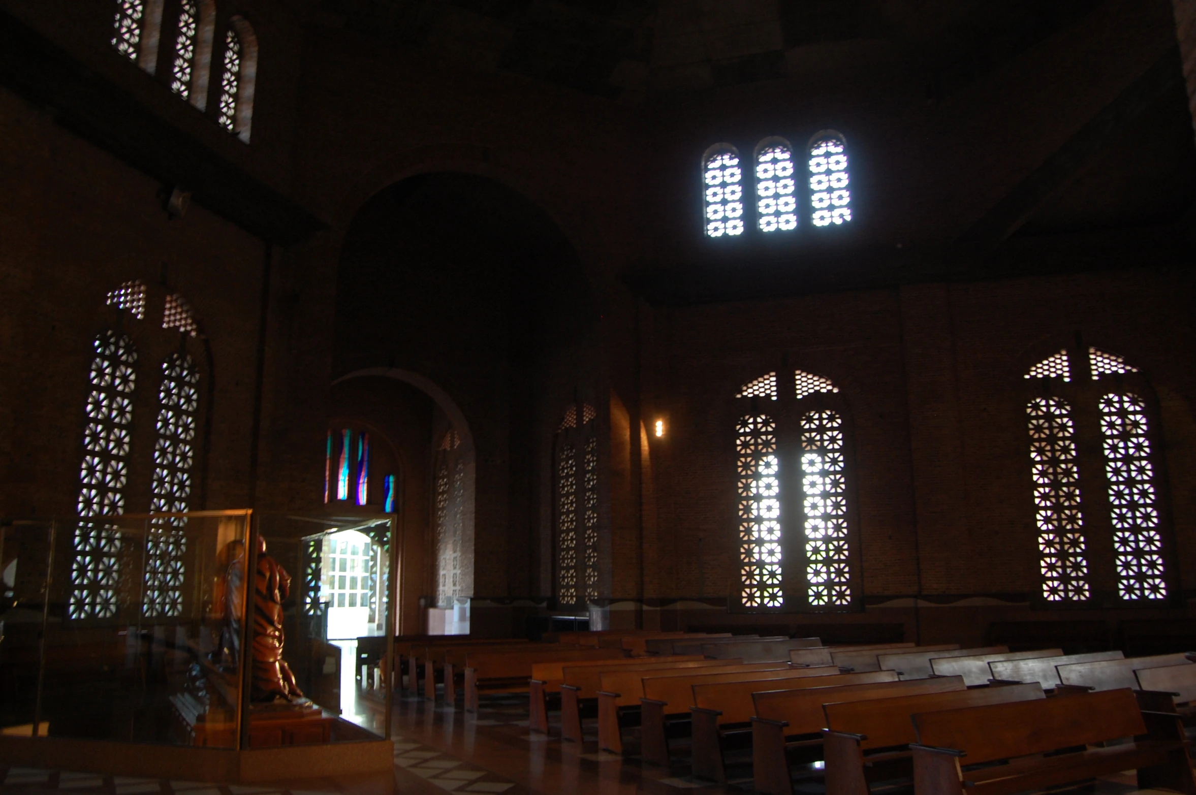 rows of wooden pews in an old church with multiple stained glass windows