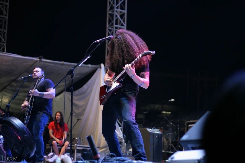 three men are playing guitars at a concert