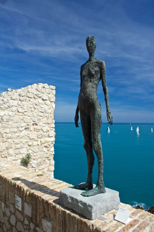 a statue on the edge of a wall near the water