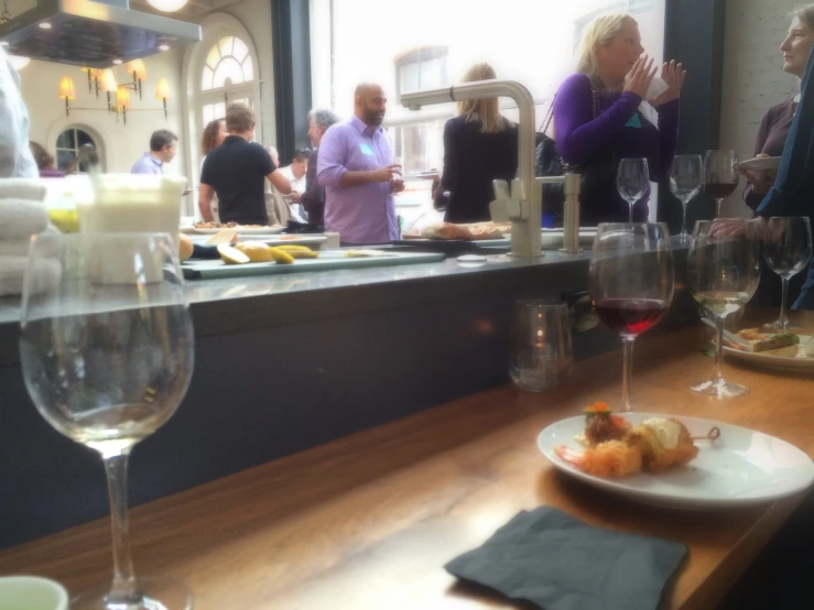 people eating a meal in a restaurant with wine glasses on the counter