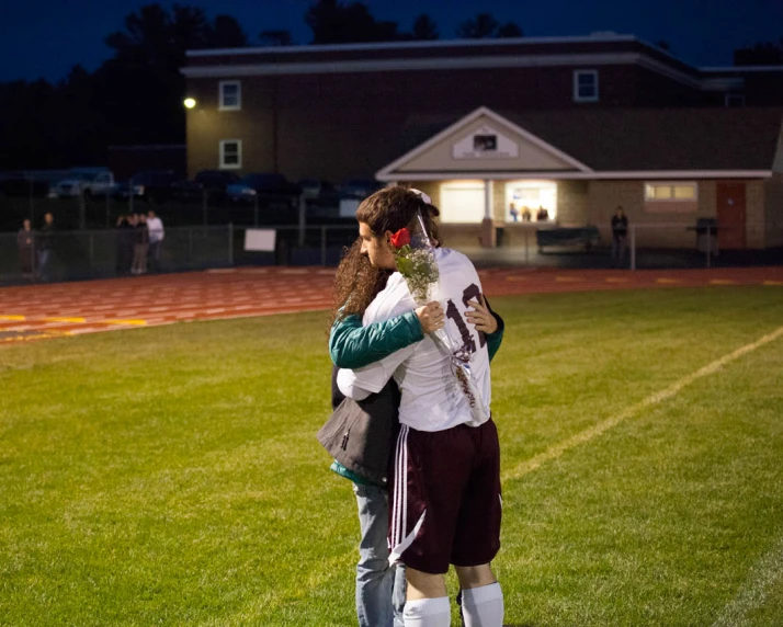 two young people on soccer field hugging