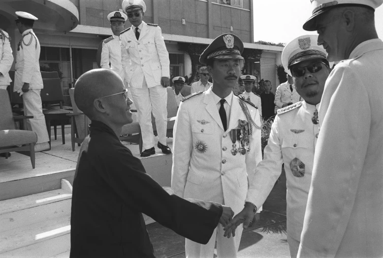 an older man in uniform shaking hands with two uniformed men