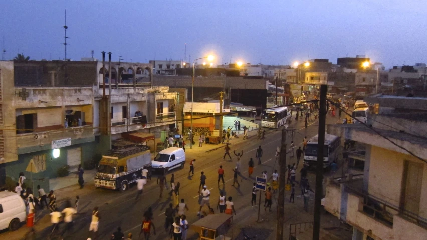 an intersection with buildings, people and cars in the evening