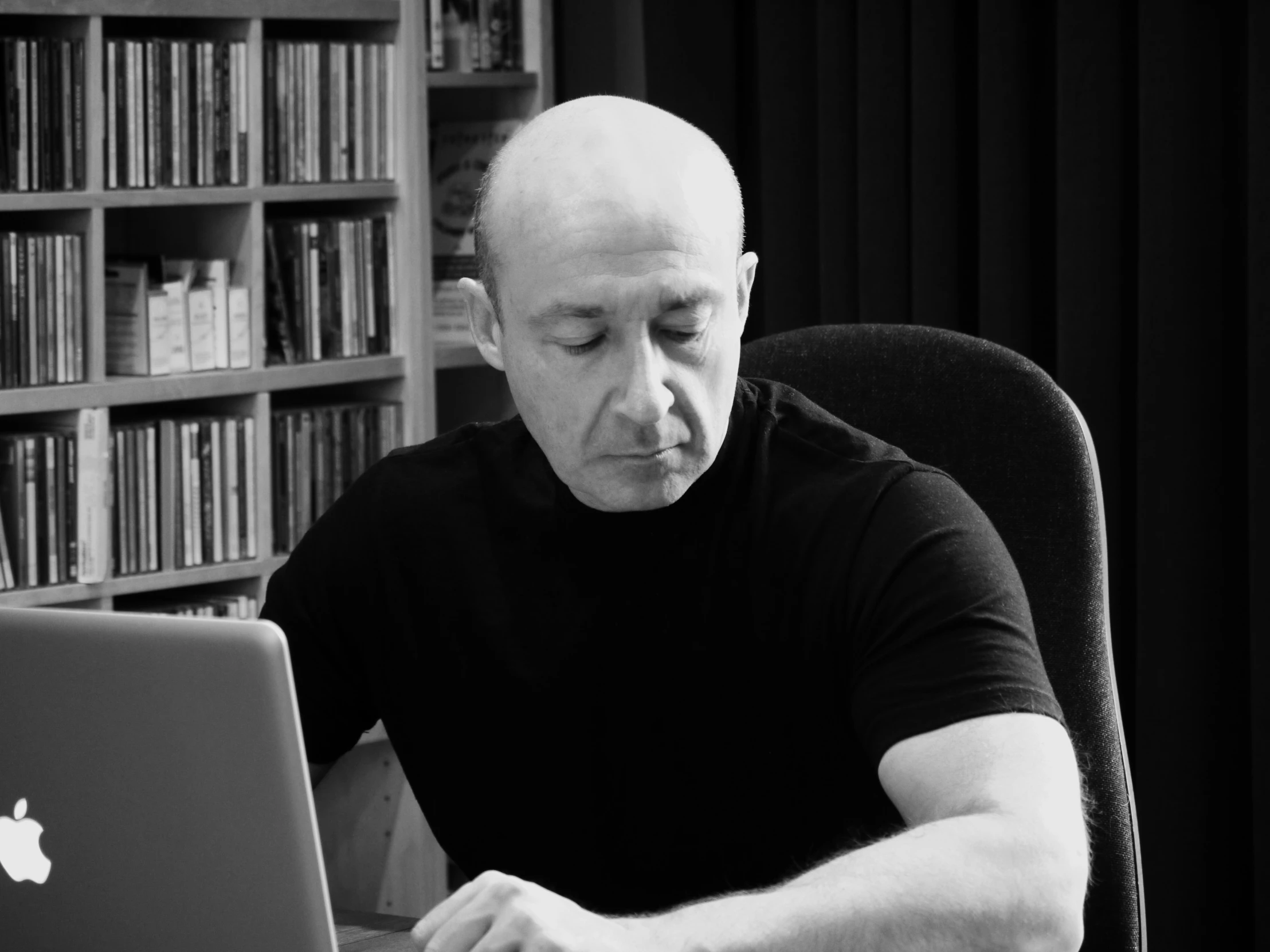 an old man at his computer in front of some books