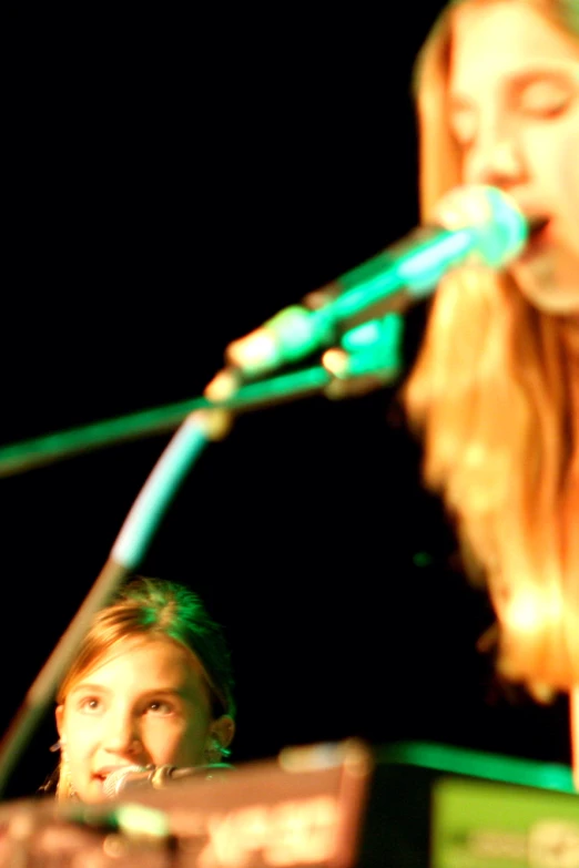 two women with long hair singing into a microphone